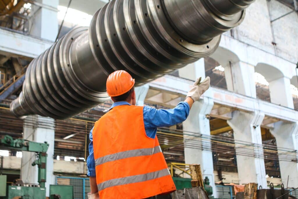 Construction supervisor guiding down some heavy machinery from a crane on site