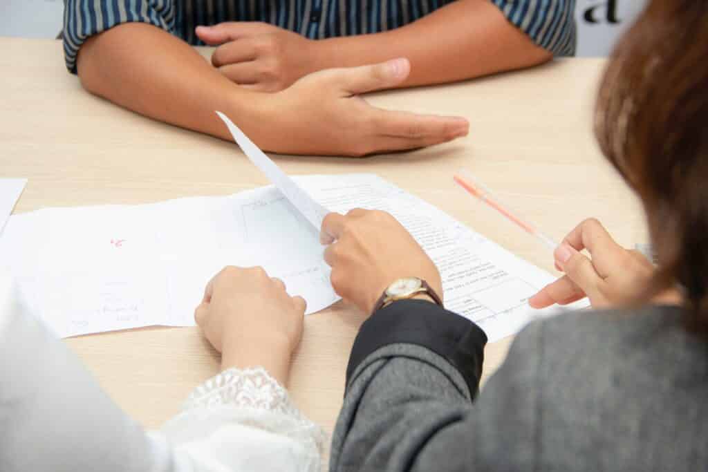 Close up of people looking through a professional resume during an interview