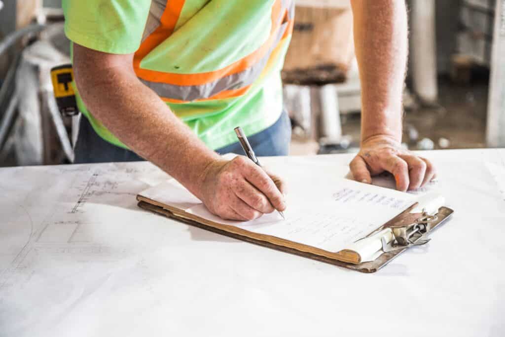 Construction worker writing down on paper after getting the job with his professional resume